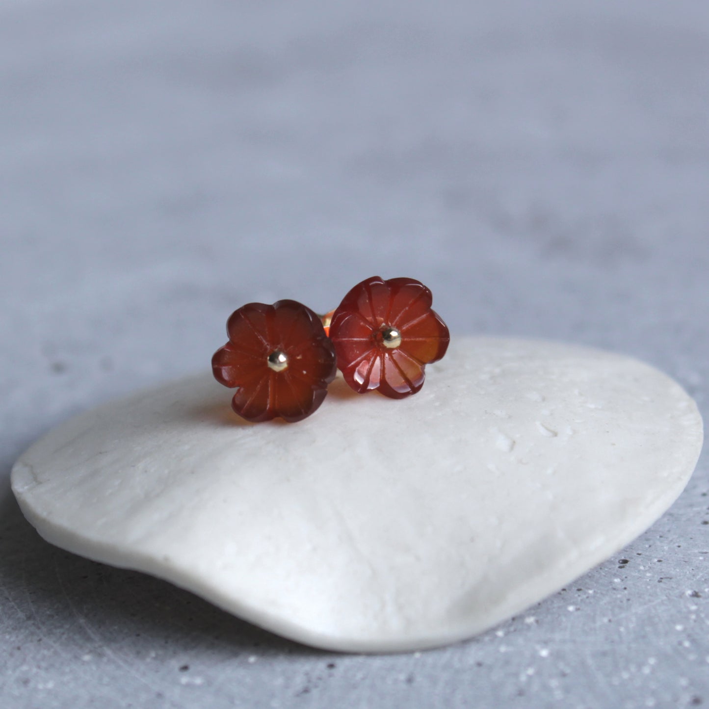 Golden earrings with an orange flower gemstone. Gouden steker oorbellen met oranje carneool.