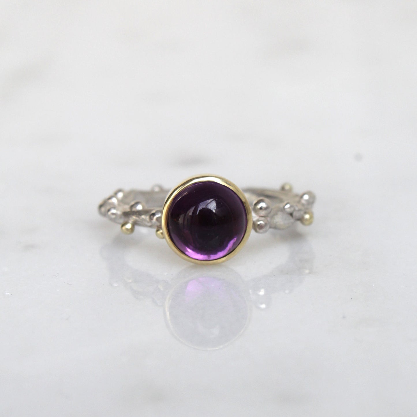 Zilveren ring met balletjes en paarse edelsteen