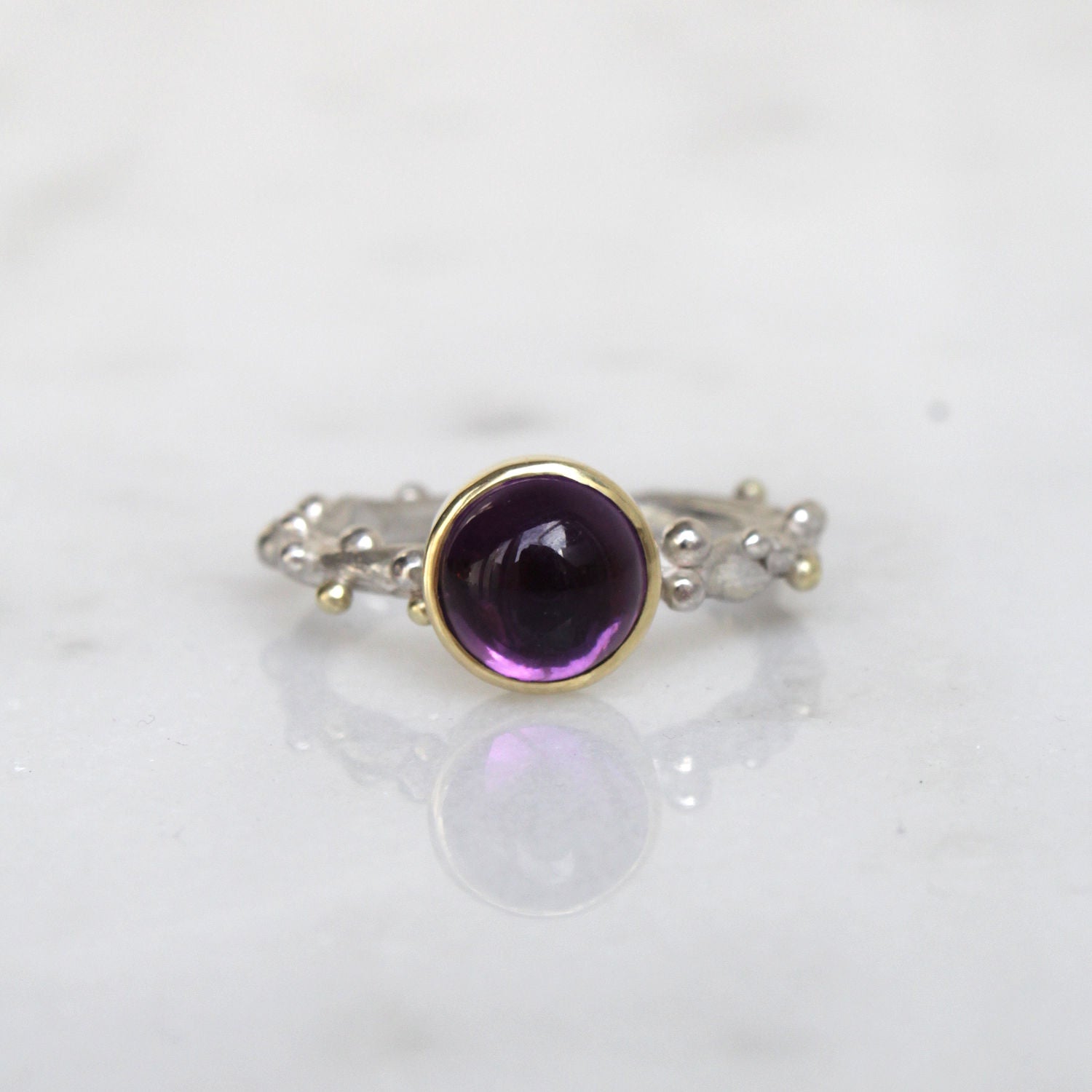 Zilveren ring met balletjes en paarse edelsteen