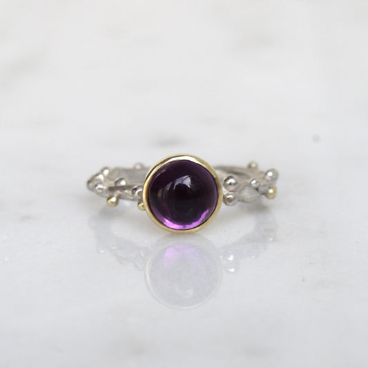 Zilveren ring met balletjes en paarse edelsteen